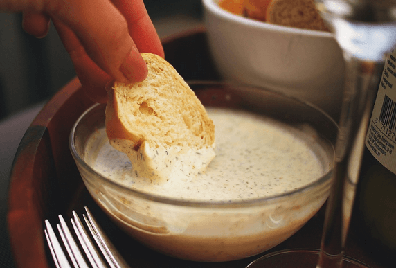 Morceau de brioche trempé dans une sauce aïoli.