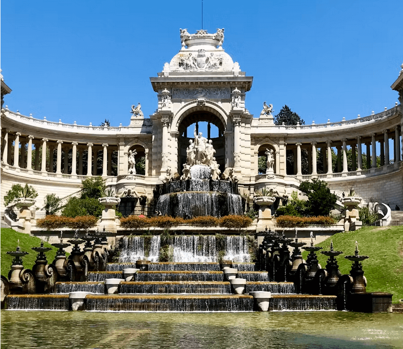 Parc Monceau à Paris avec lac, allées verdoyantes et colline surmontée d’un bâtiment pittoresque au coucher du soleil.
