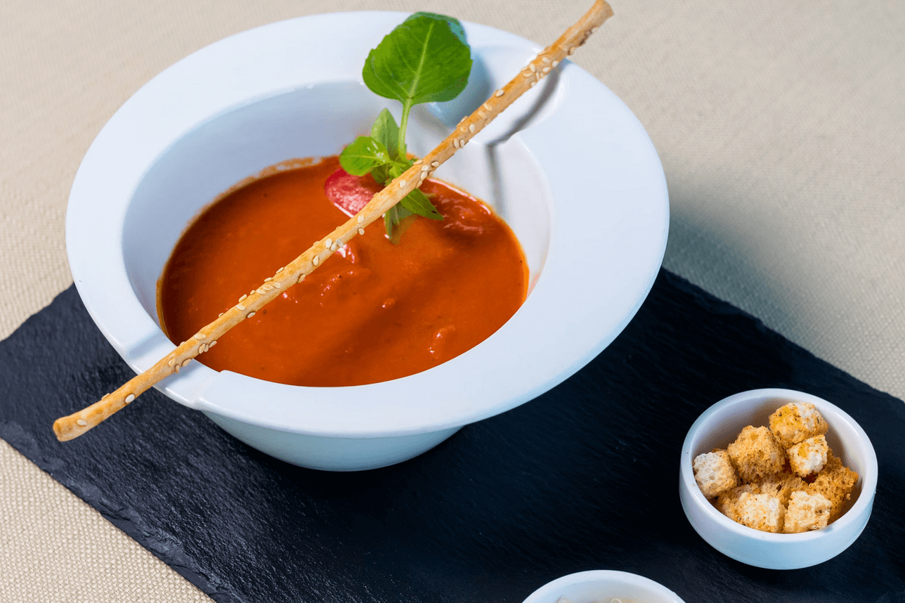Soupe de poisson servie dans un bol blanc, accompagnée de croûtons.