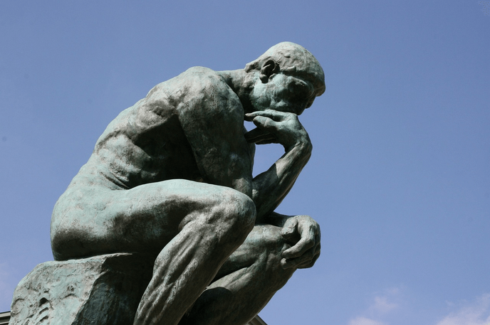 Une statue représentant un homme nu assis sur un rocher